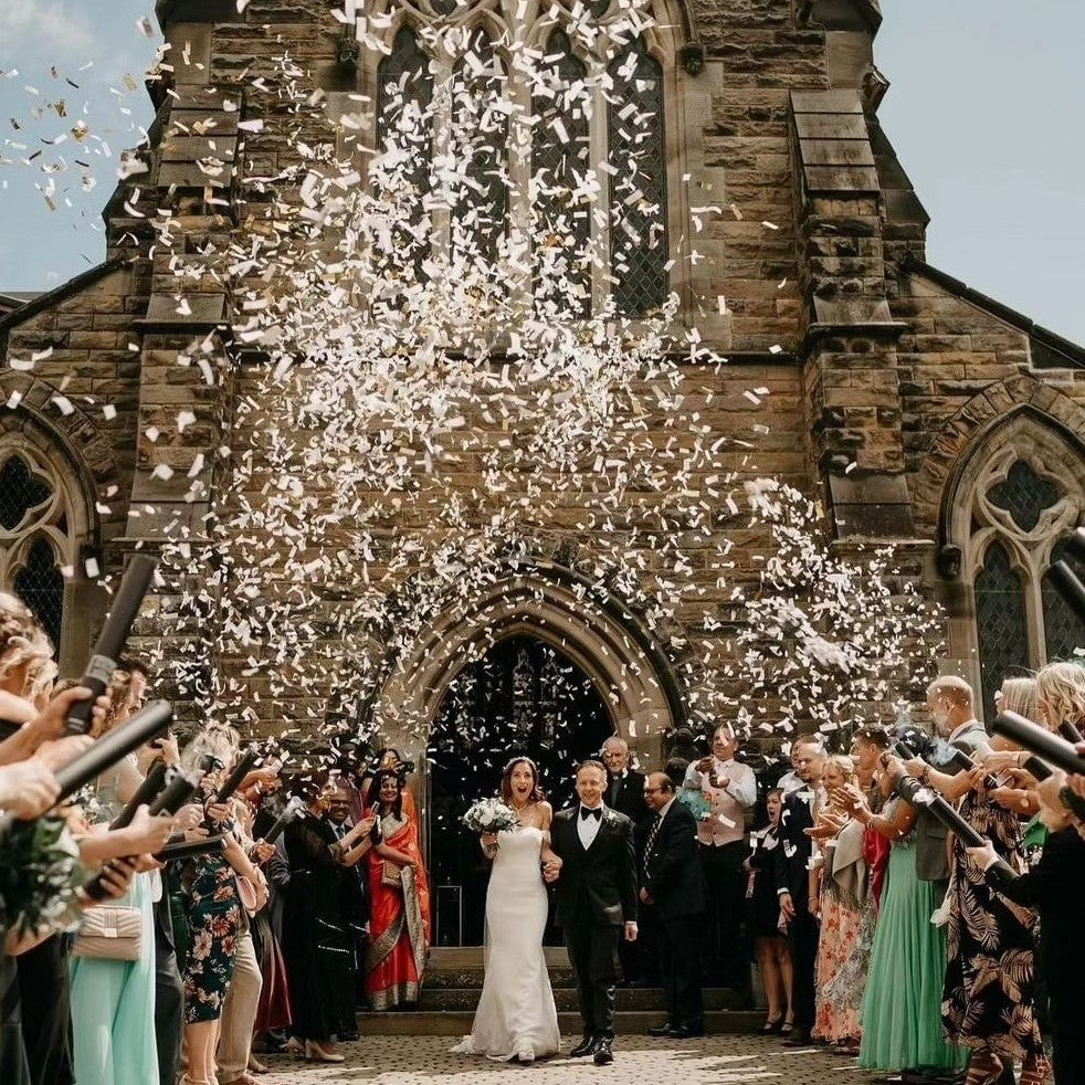 Wedding confetti cannons let off over a Bride and Groom outside a church.