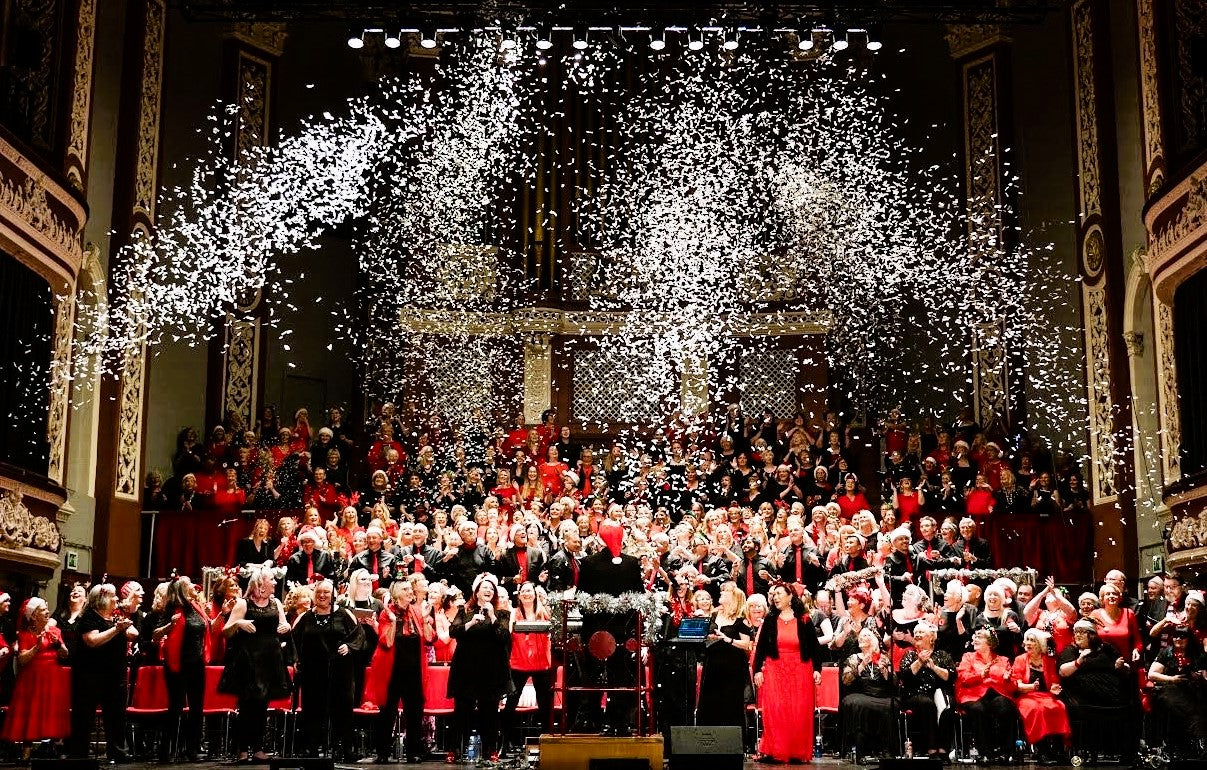 Confetti cannon fired over choir in large music venue.