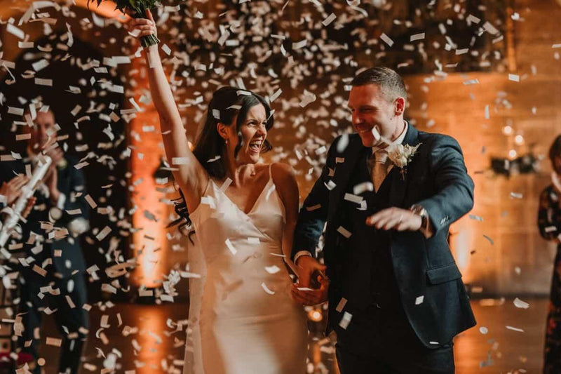 Wedding couple walking through confetti at a reception.