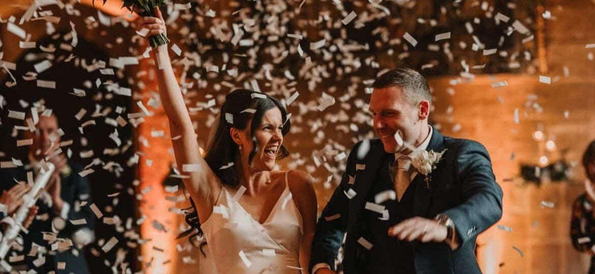 Bride and groom celebrating with confetti cannons in a romantic setting