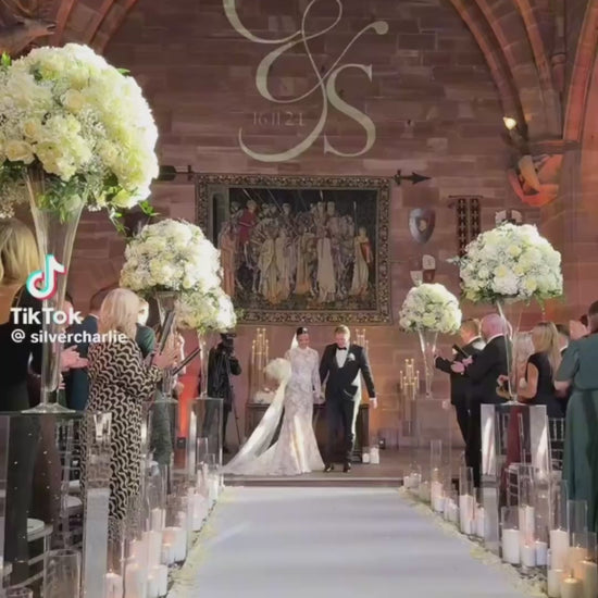 Confetti cannons with white confetti fired over bride and groom walking down isle then kissing.