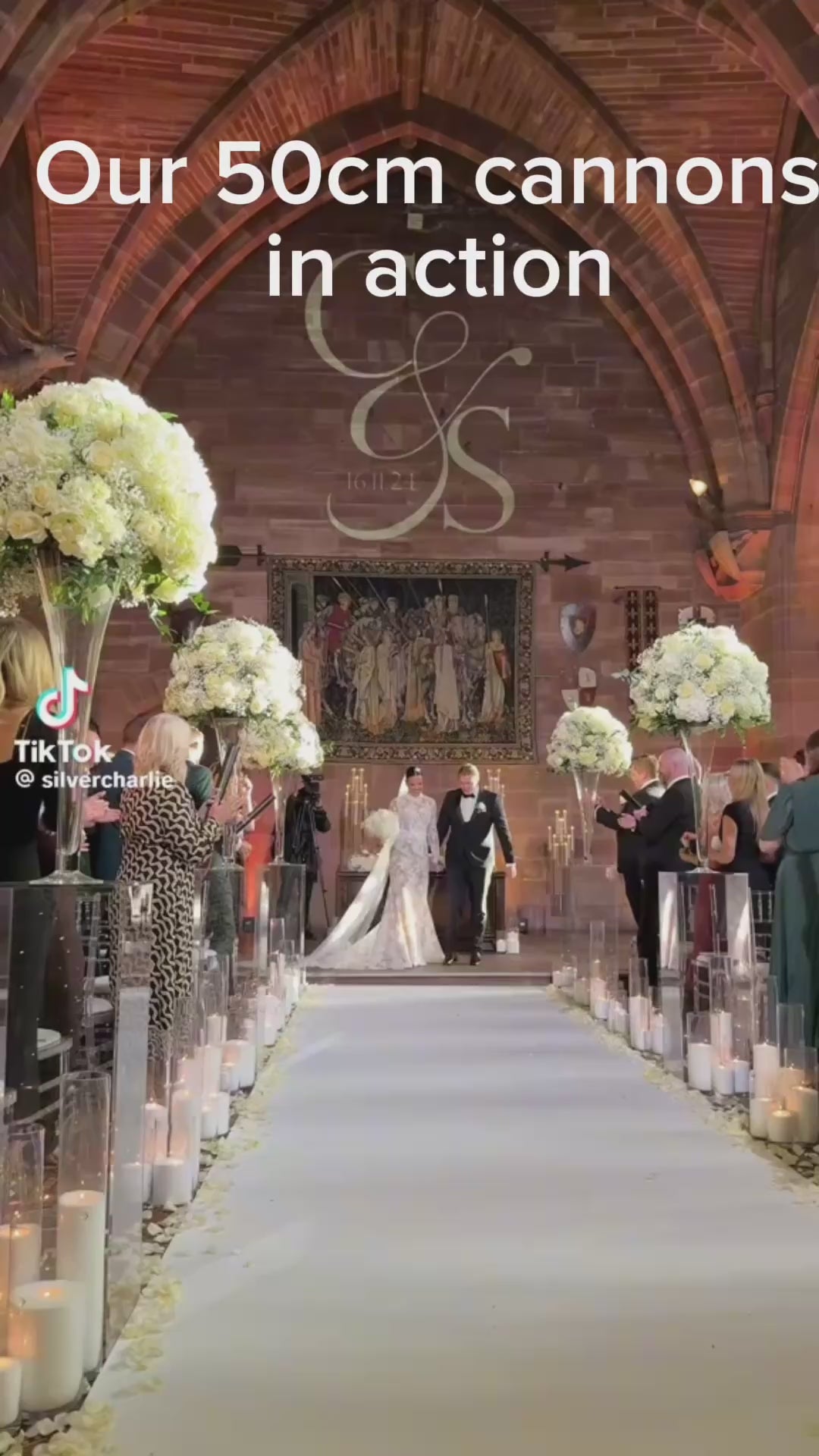 Confetti cannons with white confetti fired over bride and groom walking down isle then kissing.